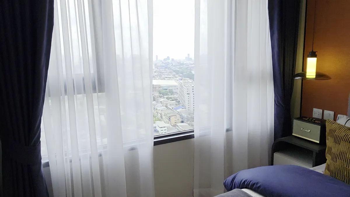 A residence bedroom with a dark headboard and a window.