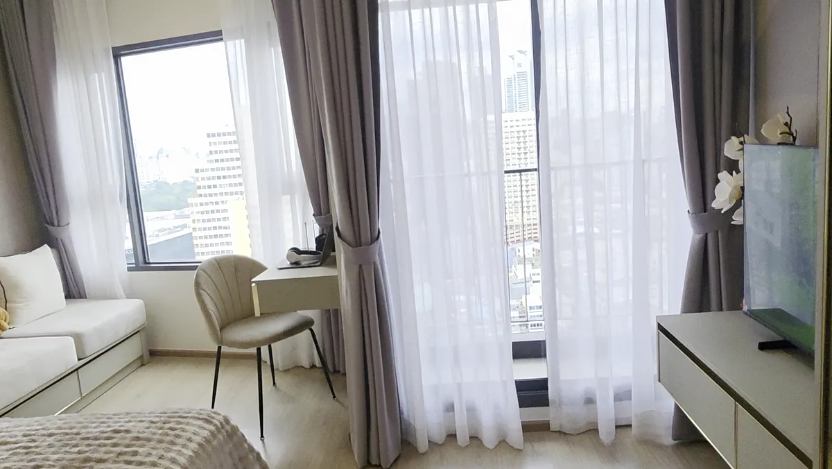A residence living area with curtains and a desk.